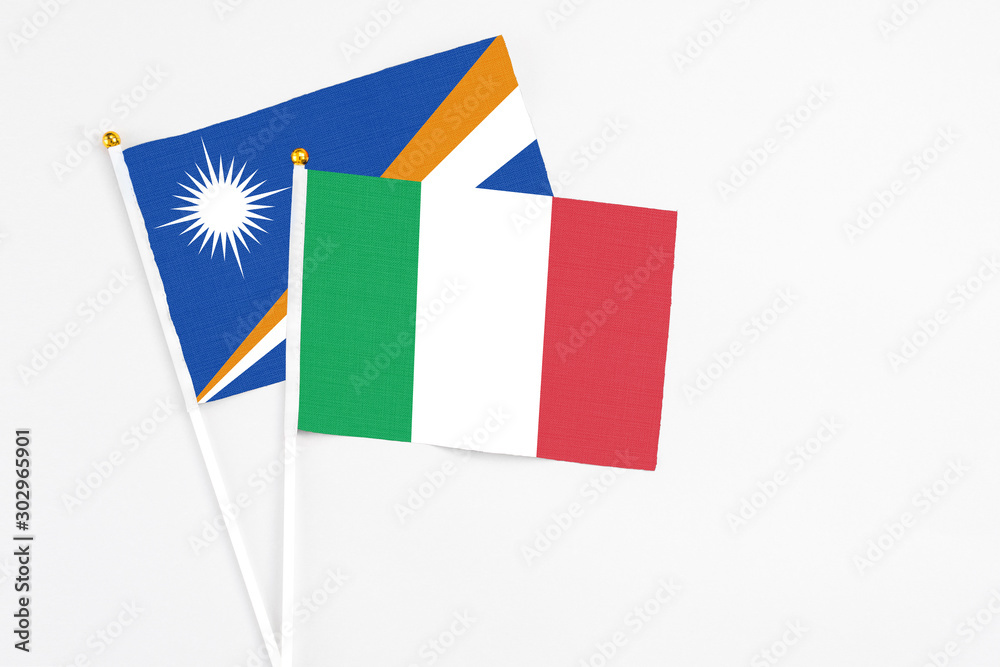 Italy and Marshall Islands stick flags on white background. High quality fabric, miniature national flag. Peaceful global concept.White floor for copy space. Italy and Marshall Islands stick flags on white background. High quality fabric, miniature national flag. Peaceful global concept.White floor for copy space.