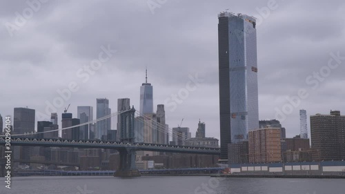 New York, USA, 2019. Skyline of Manhattan with One World Trade Center and Manhattan Bridge, many skyscrapers with overcast weather. View from East river