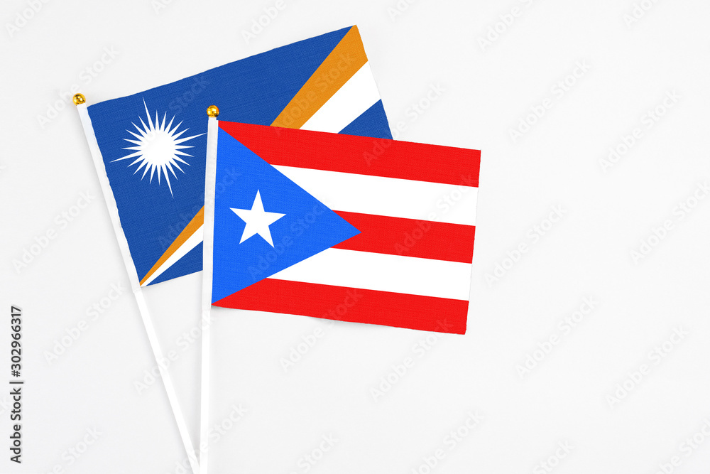 Puerto Rico and Marshall Islands stick flags on white background. High quality fabric, miniature national flag. Peaceful global concept.White floor for copy space. Puerto Rico and Marshall Islands stick flags on white background. High quality fabric, miniature national flag. Peaceful global concept.White floor for copy space.