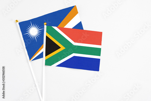 South Africa and Marshall Islands stick flags on white background. High quality fabric  miniature national flag. Peaceful global concept.White floor for copy space.