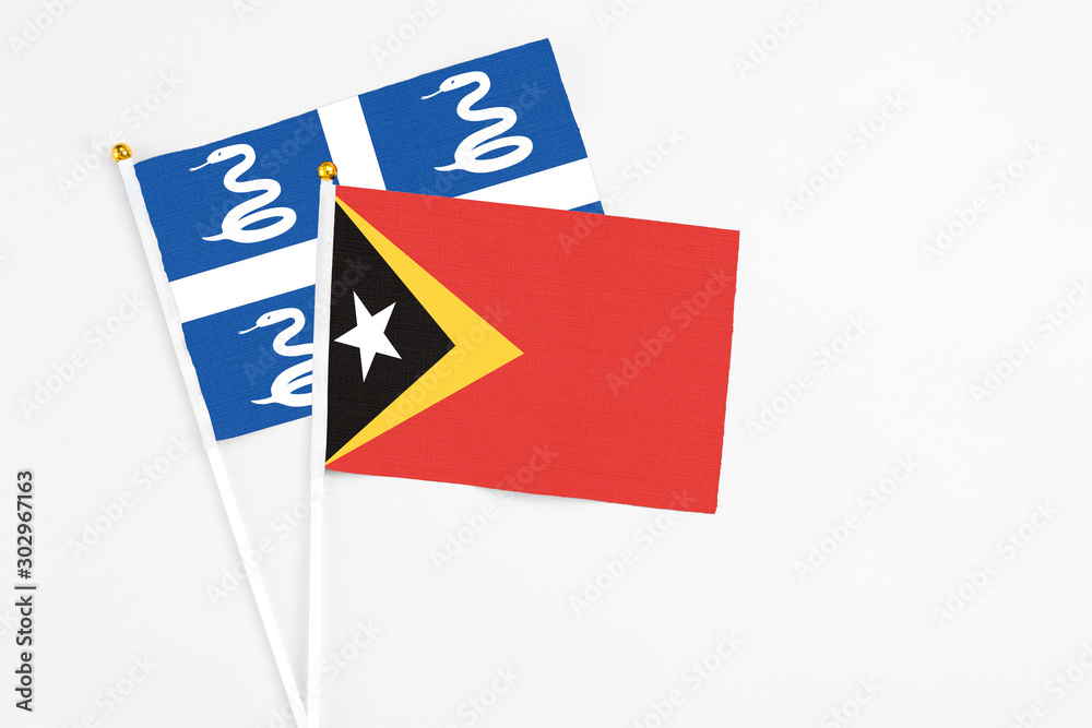 East Timor and Martinique stick flags on white background. High quality fabric, miniature national flag. Peaceful global concept.White floor for copy space. East Timor and Martinique stick flags on white background. High quality fabric, miniature national flag. Peaceful global concept.White floor for copy space.