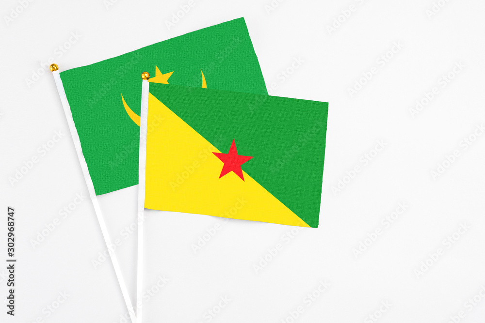 French Guiana and Mauritania stick flags on white background. High quality fabric, miniature national flag. Peaceful global concept.White floor for copy space.