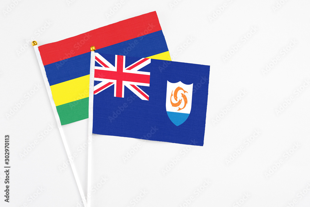 Fototapeta premium Anguilla and Mauritius stick flags on white background. High quality fabric, miniature national flag. Peaceful global concept.White floor for copy space.