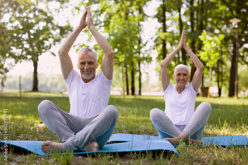 Cheerful couple meditating in the park stock photo