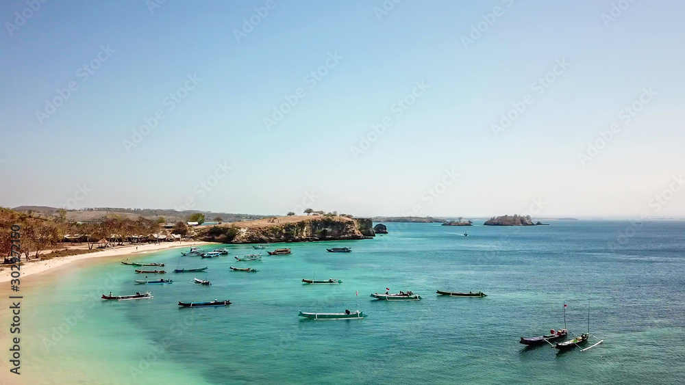An areal, drone shot with a view on an idyllic Pink Beach on Lombok, Indonesia. Many boats drifting on a calm surface of the sea. Unspoiled, hidden gem. Perfect place for peaceful, relaxed holidays An areal, drone shot with a view on an idyllic Pink Beach on Lombok, Indonesia. Many boats drifting on a calm surface of the sea. Unspoiled, hidden gem. Perfect place for peaceful, relaxed holidays