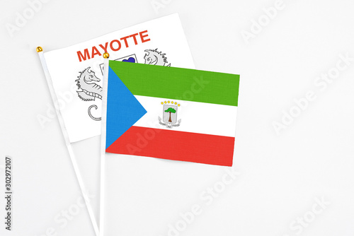 Equatorial Guinea and Mayotte stick flags on white background. High quality fabric, miniature national flag. Peaceful global concept.White floor for copy space.