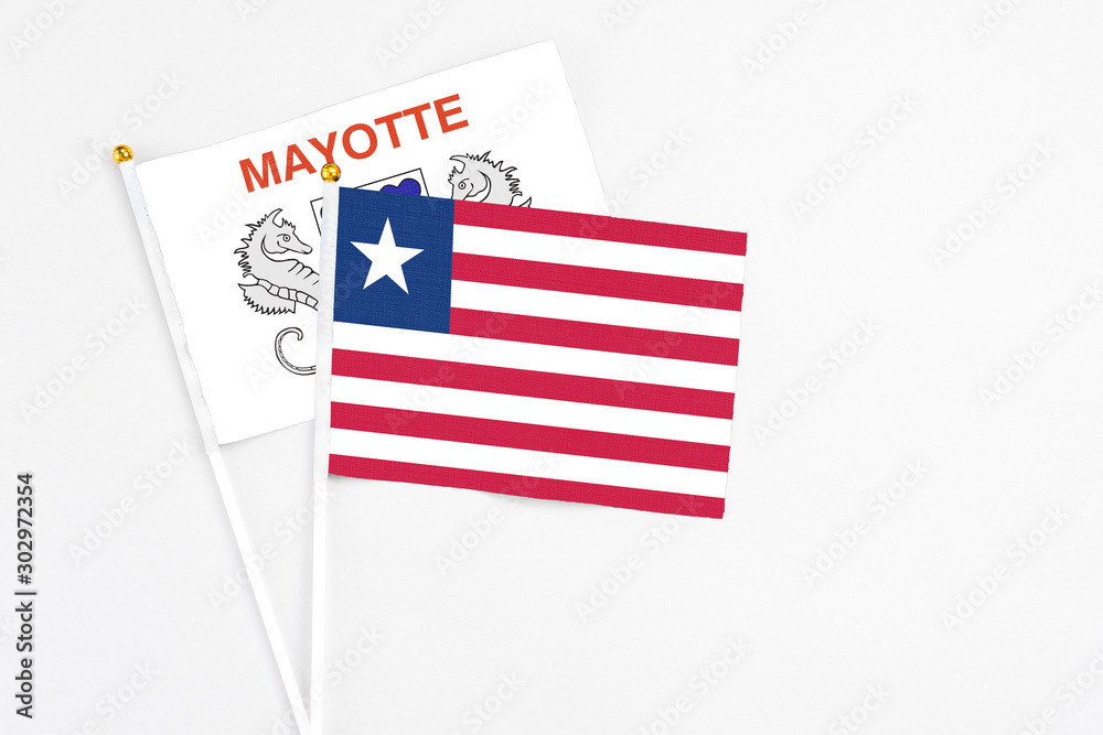 Liberia and Mayotte stick flags on white background. High quality fabric, miniature national flag. Peaceful global concept.White floor for copy space. Liberia and Mayotte stick flags on white background. High quality fabric, miniature national flag. Peaceful global concept.White floor for copy space.