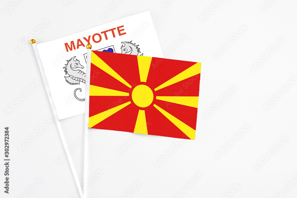 Macedonia and Mayotte stick flags on white background. High quality fabric, miniature national flag. Peaceful global concept.White floor for copy space.