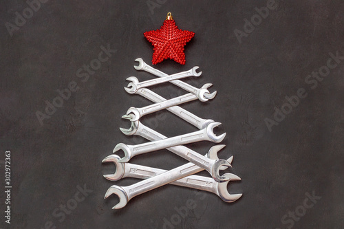 Christmas tree made of tools. Wrenches spanners on black background. Industrial greeting card and happy new year creative concept.