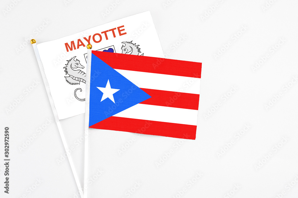 Puerto Rico and Mayotte stick flags on white background. High quality fabric, miniature national flag. Peaceful global concept.White floor for copy space.