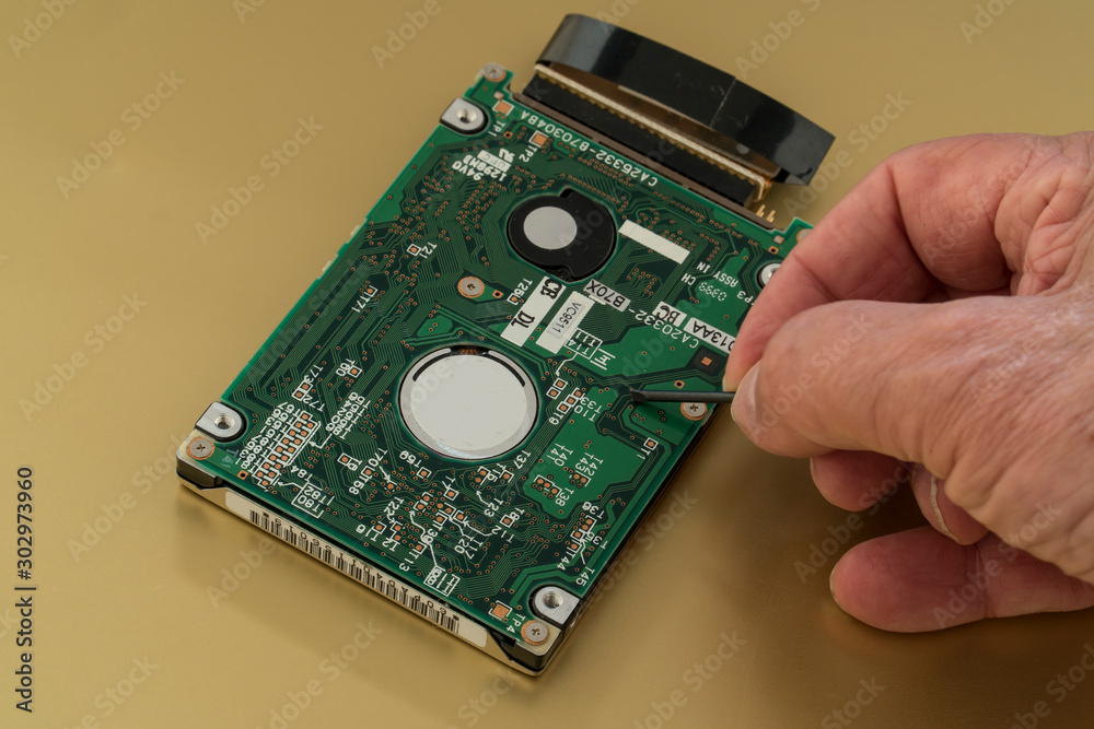 Harddrive from a laptop computer is being inspected by a technician . Harddrive from a laptop computer is being inspected by a technician .