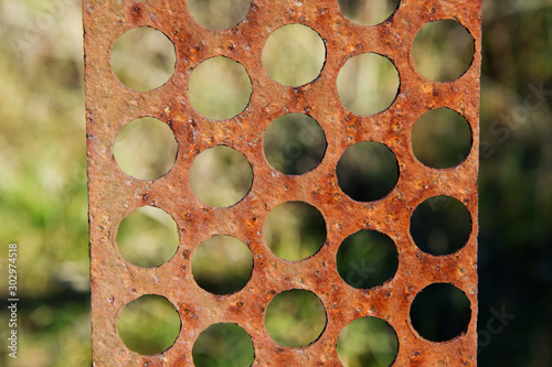 Rusty metal plate with holes texture background.