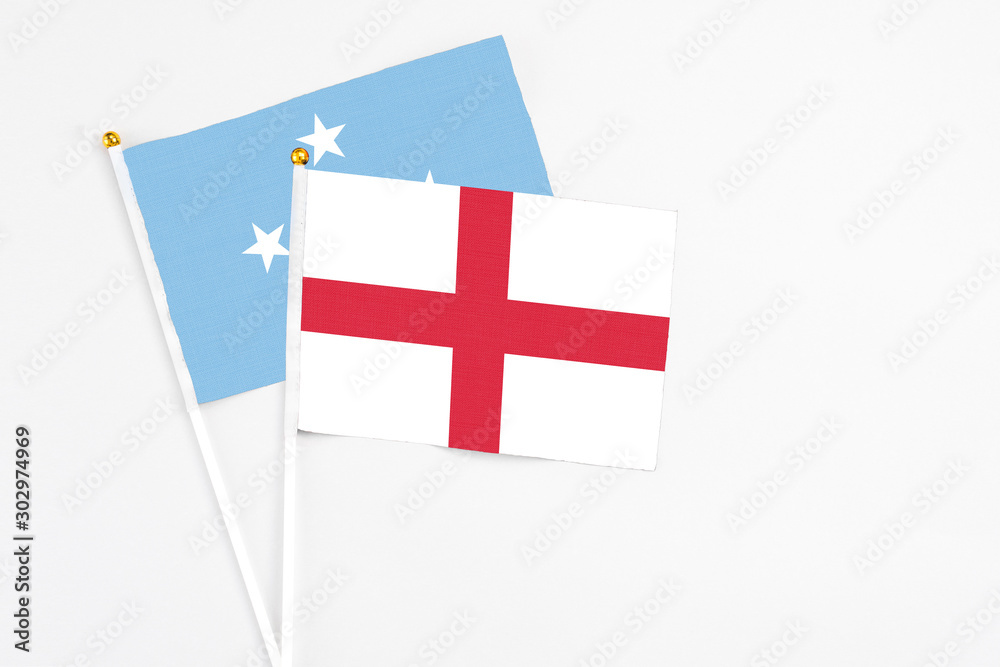 England and Micronesia stick flags on white background. High quality fabric, miniature national flag. Peaceful global concept.White floor for copy space.