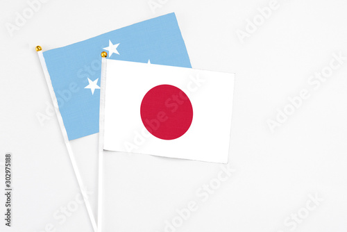 Japan and Micronesia stick flags on white background. High quality fabric, miniature national flag. Peaceful global concept.White floor for copy space. Free Download Japan and Micronesia stick flags on white background. High quality fabric, miniature national flag. Peaceful global concept.White floor for copy space. - GFXLoad