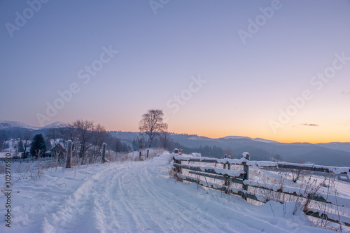 rural winter road covered with snow and mountains on horizon. beautiful winter landscape