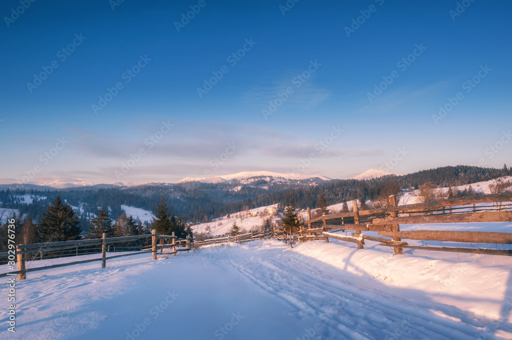 rural winter road covered with snow and mountains on horizon. beautiful winter landscape