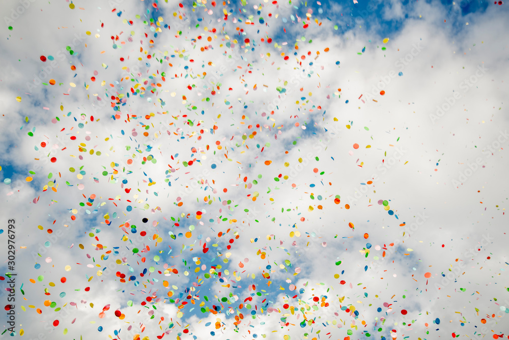 Thousands of confetti blown up on a beautiful blue sky with clouds Thousands of confetti blown up on a beautiful blue sky with clouds