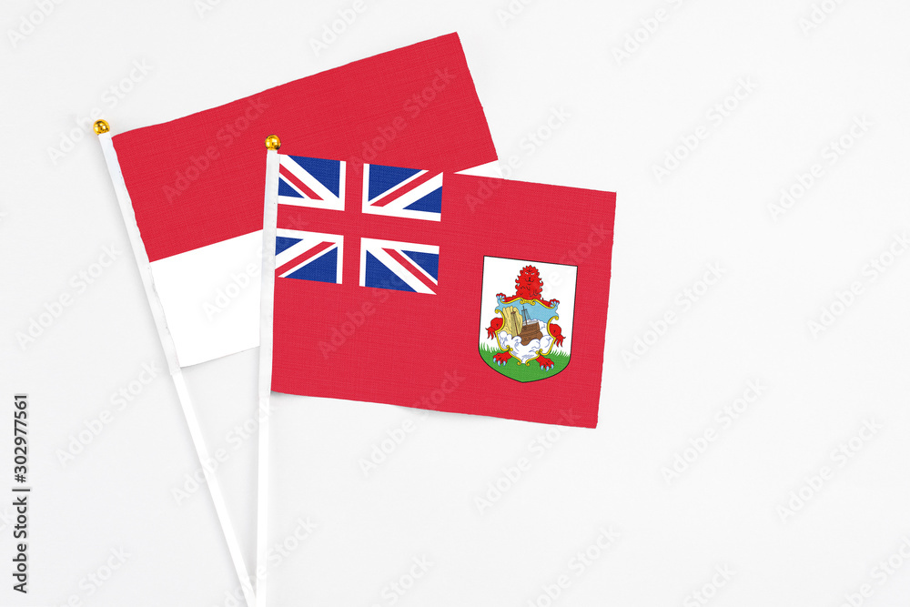 Fototapeta premium Bermuda and Monaco stick flags on white background. High quality fabric, miniature national flag. Peaceful global concept.White floor for copy space.