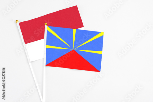 Reunion and Monaco stick flags on white background. High quality fabric, miniature national flag. Peaceful global concept.White floor for copy space.