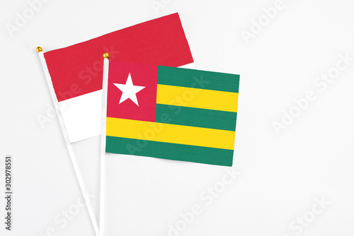 Togo and Monaco stick flags on white background. High quality fabric, miniature national flag. Peaceful global concept.White floor for copy space.