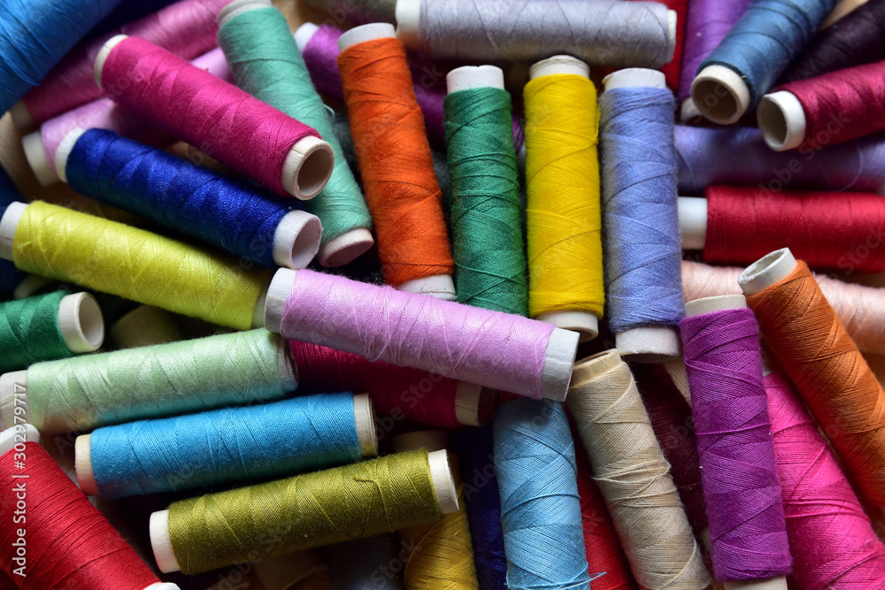 Background and texture, spools of yarns for sewing clothes, multicolored natural cotton material. Macro view from above, natural daylight. Background and texture, spools of yarns for sewing clothes, multicolored natural cotton material. Macro view from above, natural daylight.