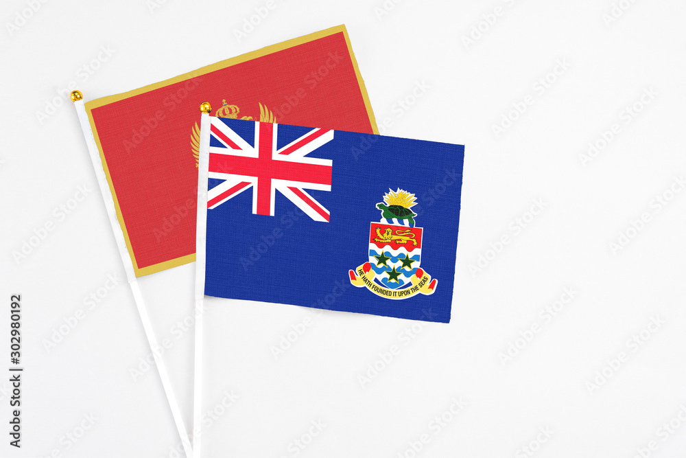 Fototapeta premium Cayman Islands and Montenegro stick flags on white background. High quality fabric, miniature national flag. Peaceful global concept.White floor for copy space.