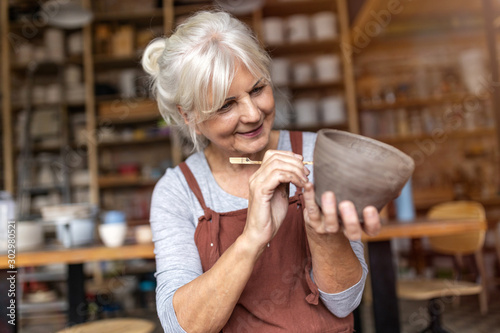 Senior woman pottery artist makes ceramics from clay photo