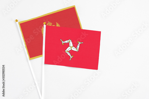 Isle Of Man and Montenegro stick flags on white background. High quality fabric, miniature national flag. Peaceful global concept.White floor for copy space.
