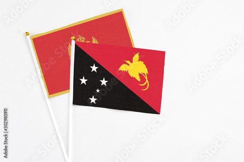 Papua New Guinea and Montenegro stick flags on white background. High quality fabric  miniature national flag. Peaceful global concept.White floor for copy space.
