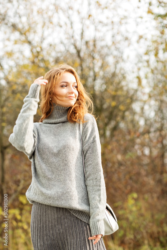 Beautiful red-haired woman in a gray skirt and a gray sweater. Fashion and style concept  lifestyle  autumn and sunlight.