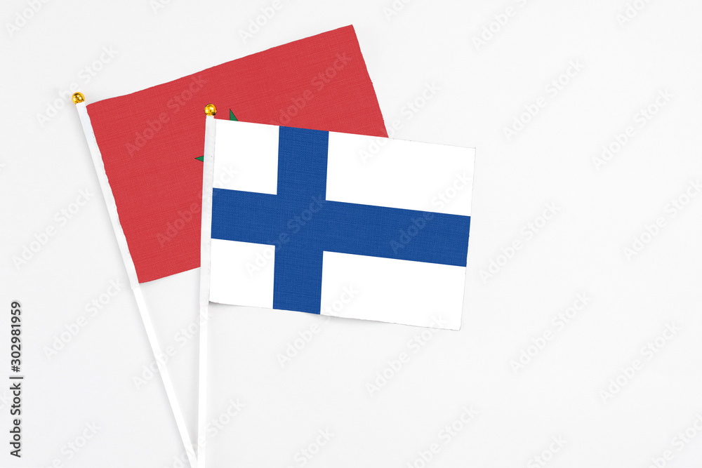 Finland and Morocco stick flags on white background. High quality fabric, miniature national flag. Peaceful global concept.White floor for copy space.