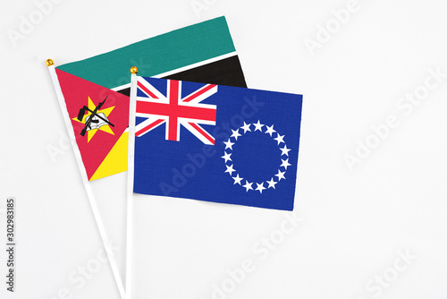 Cook Islands and Mozambique stick flags on white background. High quality fabric, miniature national flag. Peaceful global concept.White floor for copy space.