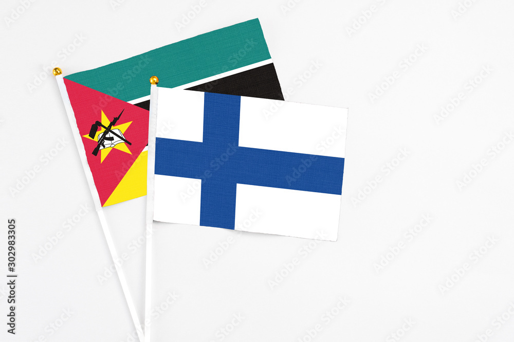 Finland and Mozambique stick flags on white background. High quality fabric, miniature national flag. Peaceful global concept.White floor for copy space.