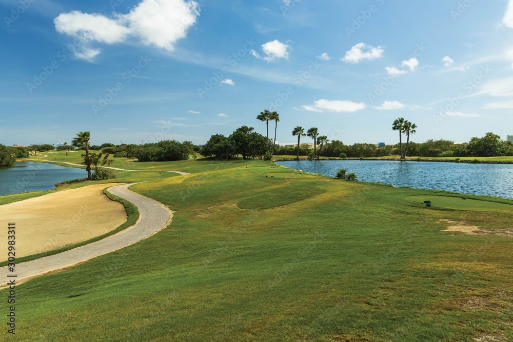 Obraz premium Beautiful nature landscape of Aruba island. Green grass, lake and blue sky with white clouds. Amazing backgrounds.