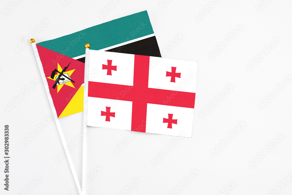 Georgia and Mozambique stick flags on white background. High quality fabric, miniature national flag. Peaceful global concept.White floor for copy space.
