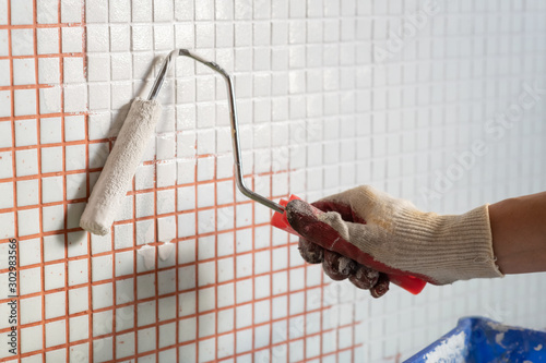 painting wall tiles with white enamel using a roller. Cheap and easy interior renovation © spritnyuk