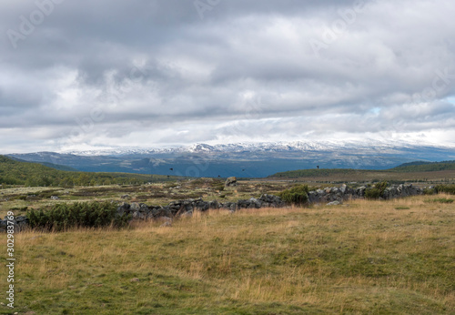 Autumn view on hills and snow capped mountains with dramatic clouds at Dovre Nasjonaalpark nature park from main road E6, Norway