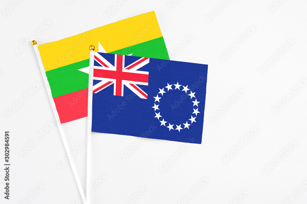 Fototapeta premium Cook Islands and Myanmar stick flags on white background. High quality fabric, miniature national flag. Peaceful global concept.White floor for copy space.