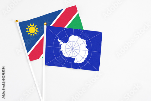 Antarctica and Namibia stick flags on white background. High quality fabric, miniature national flag. Peaceful global concept.White floor for copy space.
