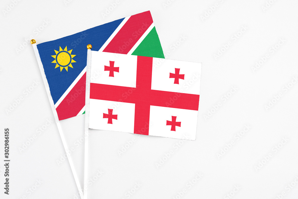 Georgia and Namibia stick flags on white background. High quality fabric, miniature national flag. Peaceful global concept.White floor for copy space.