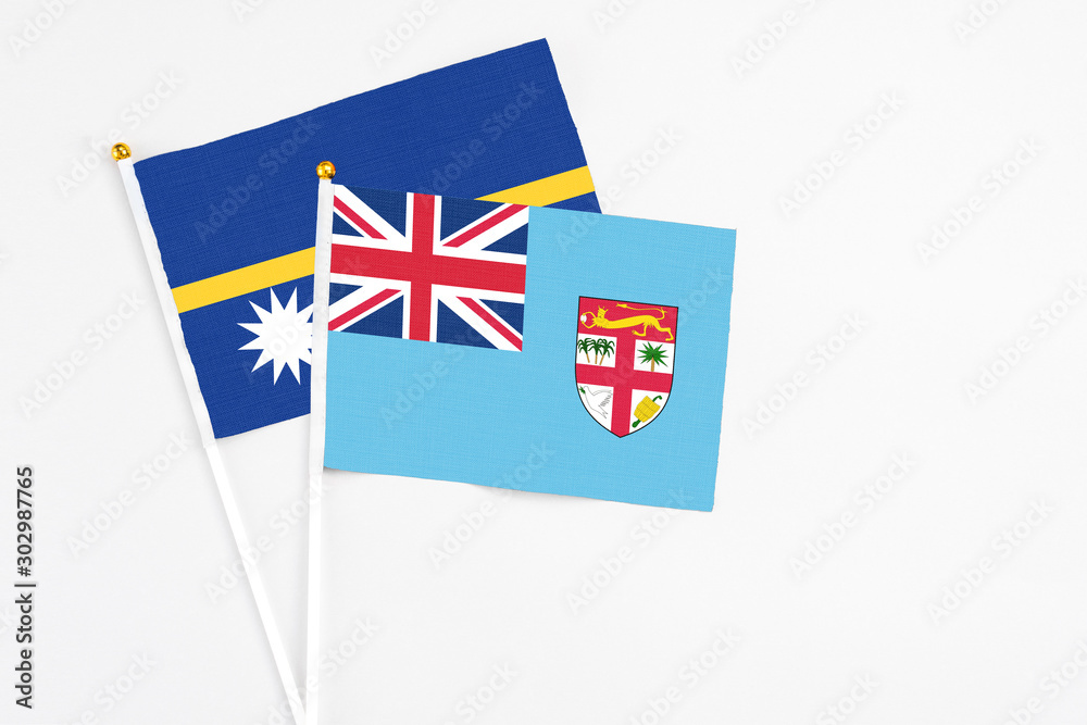Fototapeta premium Fiji and Nauru stick flags on white background. High quality fabric, miniature national flag. Peaceful global concept.White floor for copy space.