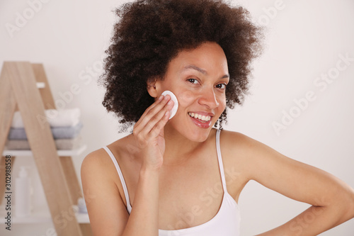 Skin cleansing routine. Woman cleaning face with lotion and cotton pad photo