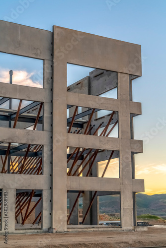 Exterior of modern building under construction against sky and clouds at sunset