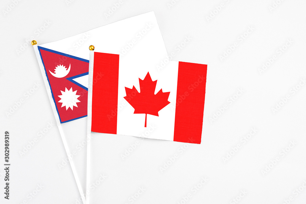 Canada and Nepal stick flags on white background. High quality fabric, miniature national flag. Peaceful global concept.White floor for copy space. Canada and Nepal stick flags on white background. High quality fabric, miniature national flag. Peaceful global concept.White floor for copy space.
