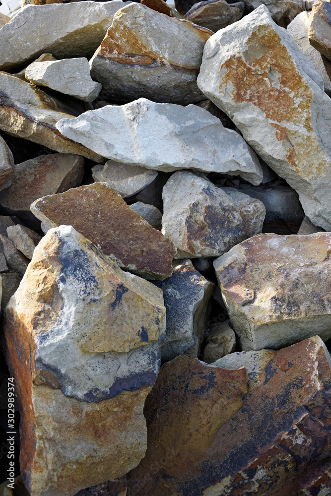 Background fragments of natural building stone - rocks with irregular flat shape, yellow and gray colored. Raw stone plates / flagstones are used in construction.