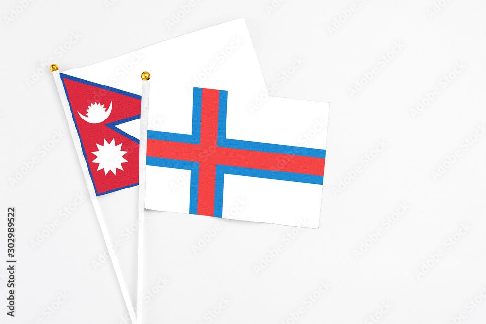 Faroe Islands and Nepal stick flags on white background. High quality fabric, miniature national flag. Peaceful global concept.White floor for copy space.