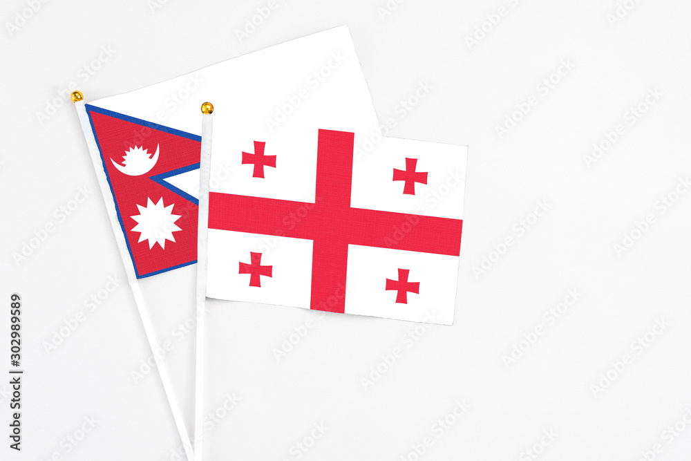 Georgia and Nepal stick flags on white background. High quality fabric, miniature national flag. Peaceful global concept.White floor for copy space.