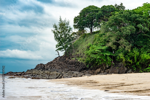Tropischer Strand mit Felsen mit wolkigem Himmel im Hintergrund