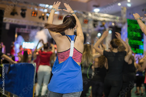 Fitness Workout in Gym: People doing Exercises in Class with Music and Teacher on Stage