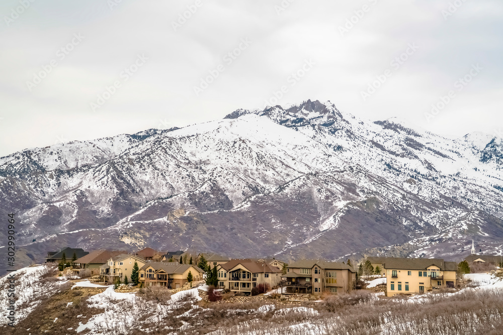 Winter landscape with homes on a hill overlooking a striking snowy mountain